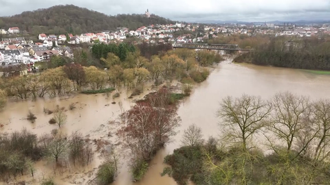 Luftaufnahme einer überfluteten Wiesenlandschaft, im Hintergrund liegt die Stadt Fulda. 