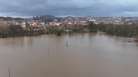 Luftaufnahme einer überfluteten Wiesenlandschaft, im Hintergrund liegt die Stadt Fulda. 