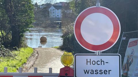 Schild weist an Ufer auf Hochwasser hin