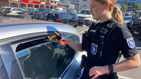 Eine Polizistin der Stadt Kassel kontrolliert die Temperatur im Auto. 