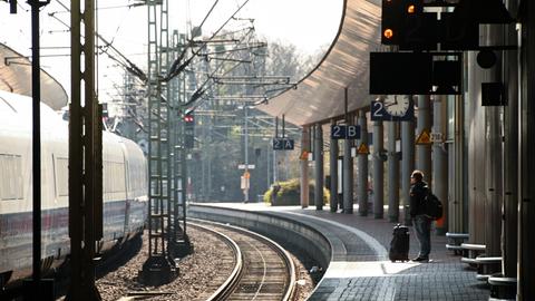 Eine Reisende steht mit ihrem Koffer am Bahnsteig in Kassel-Wilhelmshöhe.