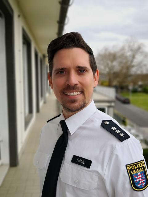 Ein Polizeihauptkommissar schaut in die Kamera, auf seinem Namensschild steht Paul.