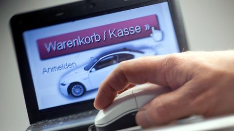 Bildschirm mit Aut und Aufschrift "Warenkorb/Kasse", davotr Hand mit Computermaus