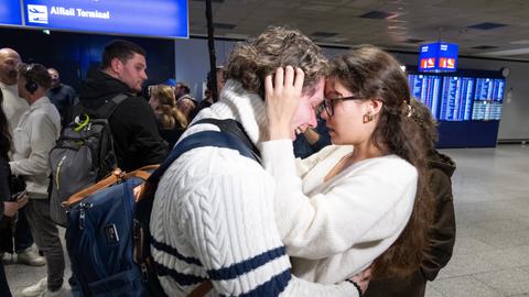 Ein Pärchen fällt sich auf dem Frankfurter Flughafen in die Arme