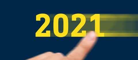 Grafik: Eine gelbe 2021 wird mit einem Finger auf einem dunkelblauen Hintergund scheinbar von rechts nach links ins Bild gewischt.