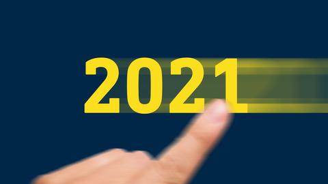 Grafik: Eine gelbe 2021 wird mit einem Finger auf einem dunkelblauen Hintergund scheinbar von rechts nach links ins Bild gewischt.