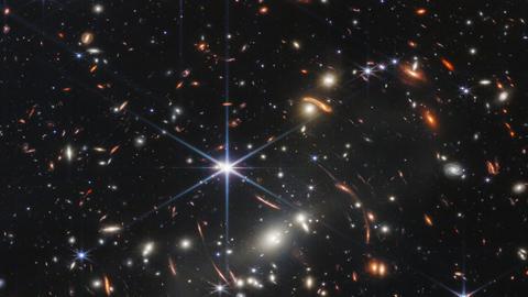 Im dunklen Weltall sind bunte Sterne und Galaxien zu sehen.