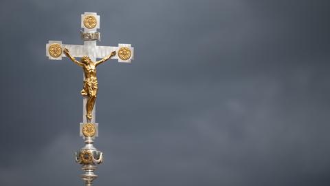 Ein Kruzifix ist beim Schlussgottesdienst des 102. Deutschen Katholikentags vor dunklen Wolken zu sehen.
