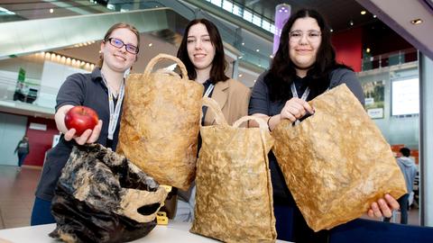 Anja Armstrong (l-r), Jennifer Boronowska und Seyma Celik aus Rüsselsheim mit ihrer kompostierbaren Einwegtüten aus Biokunststoff.