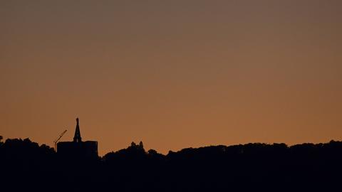 Dunkel zeichnet sich der Herkules mit abgeschalteteter Außenbeleuchtung vor dem Abendhimmel ab. 