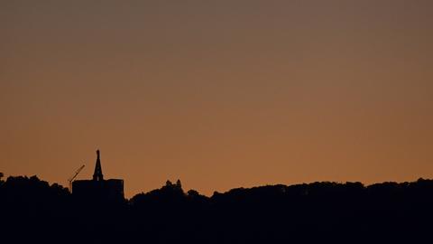 Dunkel zeichnet sich der Herkules mit abgeschalteteter Außenbeleuchtung vor dem Abendhimmel ab. 