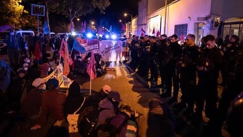 Aktivisten demonstrieren vor dem Firmengelände vom Rüstungsunternehmen Krauss-Maffei Wegmann, die Polizei sichert ein Eingangstor.