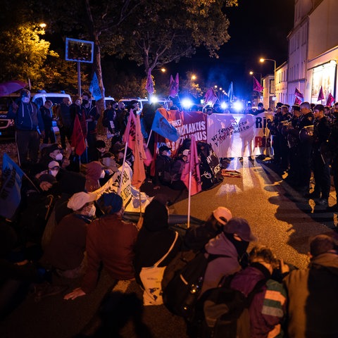 Aktivisten demonstrieren vor dem Firmengelände vom Rüstungsunternehmen Krauss-Maffei Wegmann, die Polizei sichert ein Eingangstor.