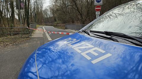 Polizeiwagen stehen auf einer Straße zwischen mehrstöckigen Wohngebäuden. Das Foto ist aus einem höher gelegenen Fenster heraus aufgenommen.