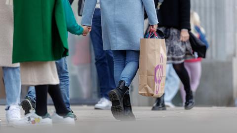 Symbolfoto: Menschen flanieren mit einer Einkaufstausche durch die Stadt. 
