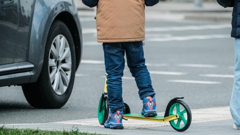 Kind auf Roller am Straßenrand