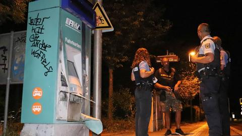 Ein beschädigter Fahrkartenautomat, daneben stehen Polizisten.