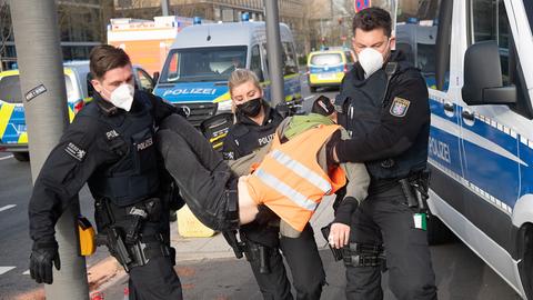Polizisten tragen einen Demonstranten der Gruppe "Letzte Generation" von der Straße.