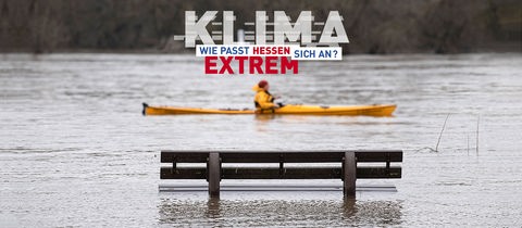 Hochwasser mit Kanufahrer vor Parkbank im Wasser mit Logo