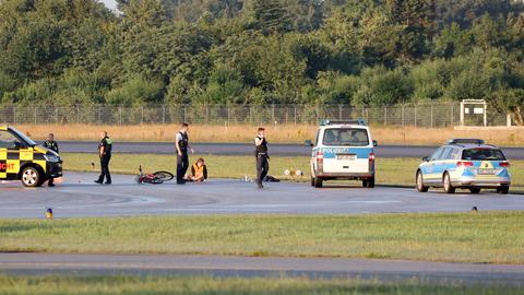 Eine Klimaaktivistin ist auf dem Vorfeld festgeklebt, Polizei steht schon daneben.