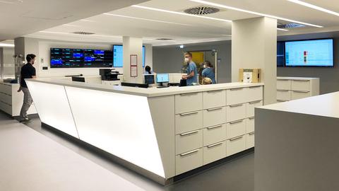 Foto: Counter einer Pflegestation mit vielen Monitoren und arbeitssamen Pflegepersonal.