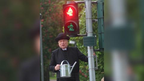 Mann als Pfarrer verkleidet vor Ampel