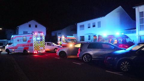 Mehrere Rettungswägen stehen im Dunkeln vor einem Mehrfamilienhaus.