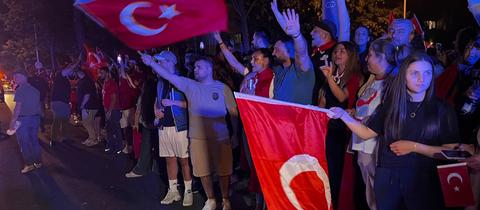 Erdoğan-Anhänger am türkischen Konsulat in Frankfurt. Türkische Fahnen werden geschwenkt.