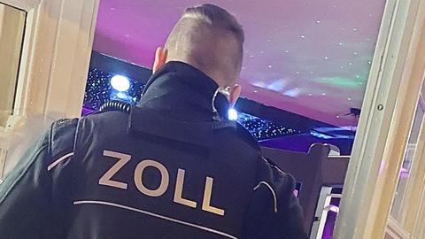 Ein Zollmitarbeiter steht vor dem Eingang einer Bar.