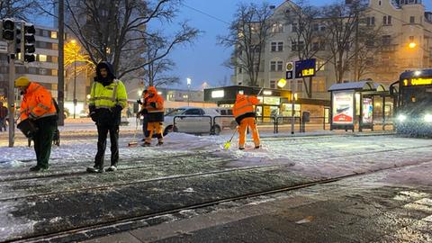 Städtische Mitarbeiter in Kassel entfernen die Schienen von Schnee und Eis.