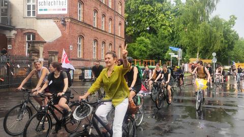 Viele Fahrradfahrenden auf einer Straße, die teils in die Kamera winken.