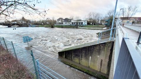 Reißender Fluss, daneben eine Schleuse mit Brücke.