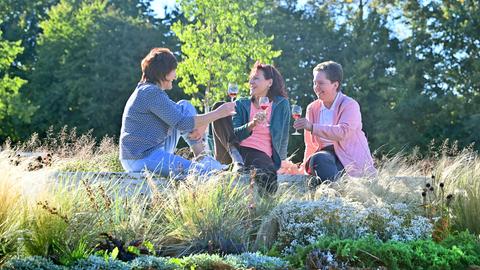 Drei Frauen sitzen auf dem Gelände der Landesgartenschau Fulda und trinken Wein