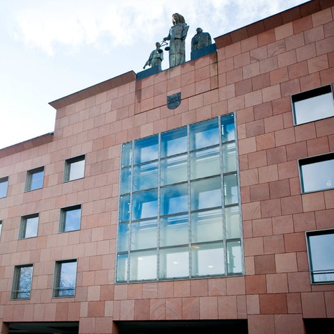 Schnörkelloses Gebäude von außen mit Justizia Figur am oberen Rand der Fassade.