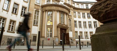 Das Land- und Amtsgericht Frankfurt von der Straße aus fotografiert. Davor ist ein Mensch zu sehen, wie er vorbeiläuft. Die Tür zum Gebäude steht offen.