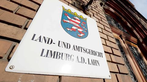 Schild mit der Aufschrift "Land- und Amtsgericht Limburg a.L." an einer Backsteinwand neben einer Tür.