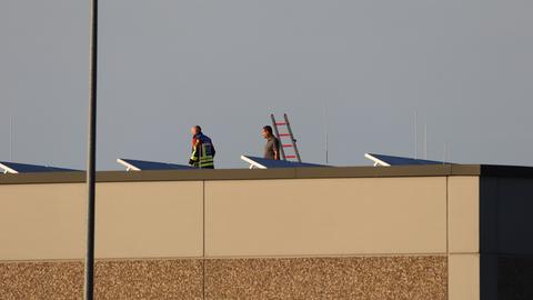 Die Feuerwehr überprüft das Dach nach einem Brand einer Lagerhalle in Langenselbold.