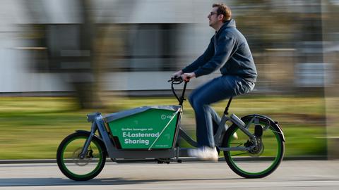 Mann mit Elektro-Lastenrad, auf dem Sharing steht