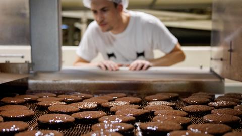 Lebkuchen, frisch produziert: Frisch mit einer Schokoglasur überzogene und gebackene Lebkuchen laufen auf einem Band. 