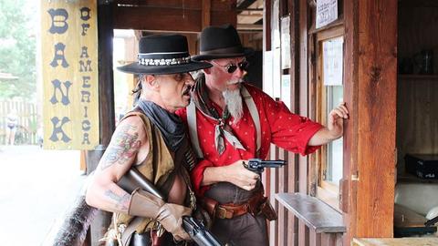 Zwei Cowboys, einer mit Waffe, stehen vor einer Tür.