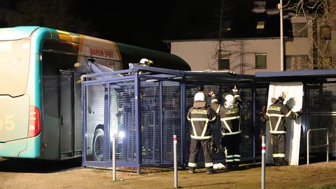 Ein Linienbus steht an einer Haltestelle. Ein Seitenfenster ist von einem Metallteil durchbohrt.