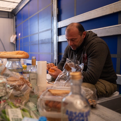 Eine Gebetskerze steckt am Ostersonntag in einem Brot auf einem provisorischen Tisch, an dem Lastwagenfahrer Zurab aus Georgien in einem Lkw auf der Raststätte Gräfenhausen sitzt.