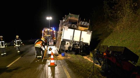 Der Lkw steht nach dem Unfall in einem Straßengraben. Daneben Einsatzkräfte.