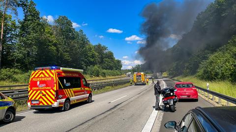 Rauch steigt aus brennendem Lkw auf Autobahn, Rettungskräfte vor Ort