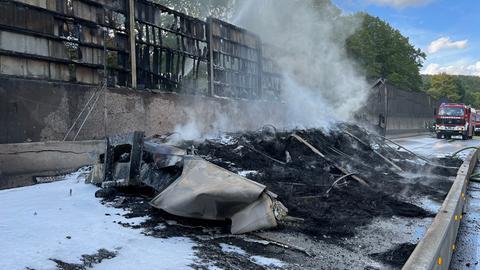 Ein abgebranntes Lkw-Wrack steht auf einer Autobahn.