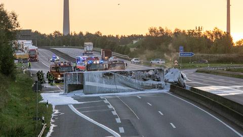 Ausgebranntes Lkw-Gerippe in Löschschaum querliegend auf Autobahn mit Feuerwehrwagen