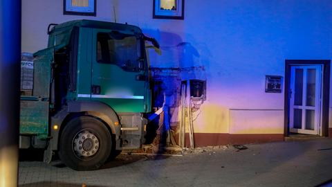 Das Bild zeigt die Fahrerkabine eines Lkws vor einer beschädigten Hauswand.