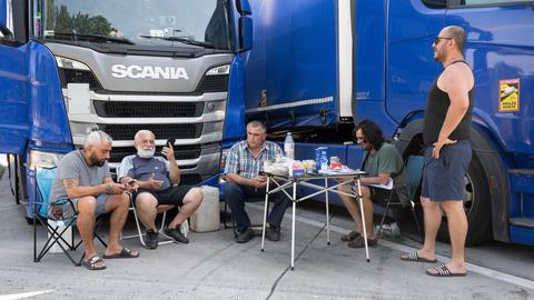 Lkw-Fahrer sitzen am Mittwoch auf der Raststätte Gräfenhausen vor ihren Fahrzeugen zusammen.