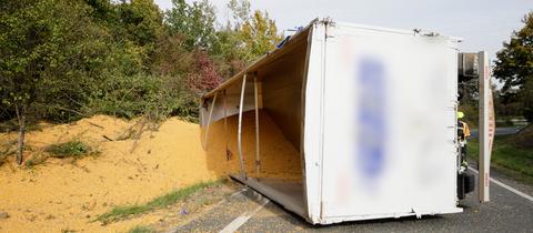 Umgekippter Lkw auf Straße, Mais liegt auf Straße und in Böschung