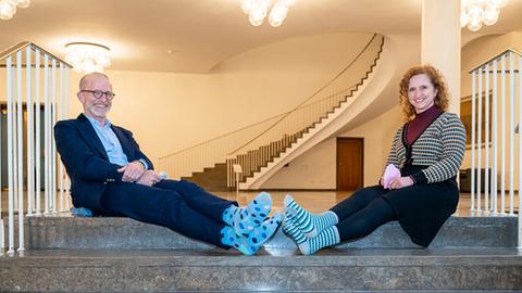Ein Mann und eine Frau mit bunten Socken sitzen auf einer Treppe.